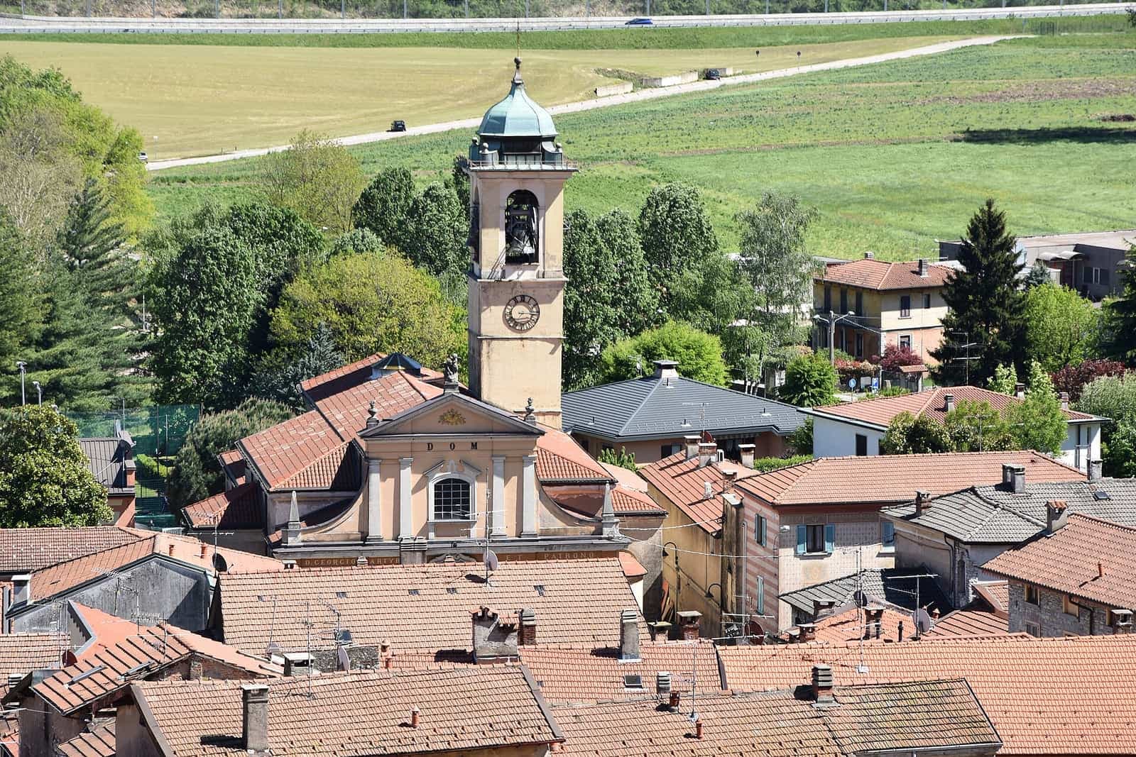 I tetti di Bisuschio con il campanile della chiesa, tra i prati