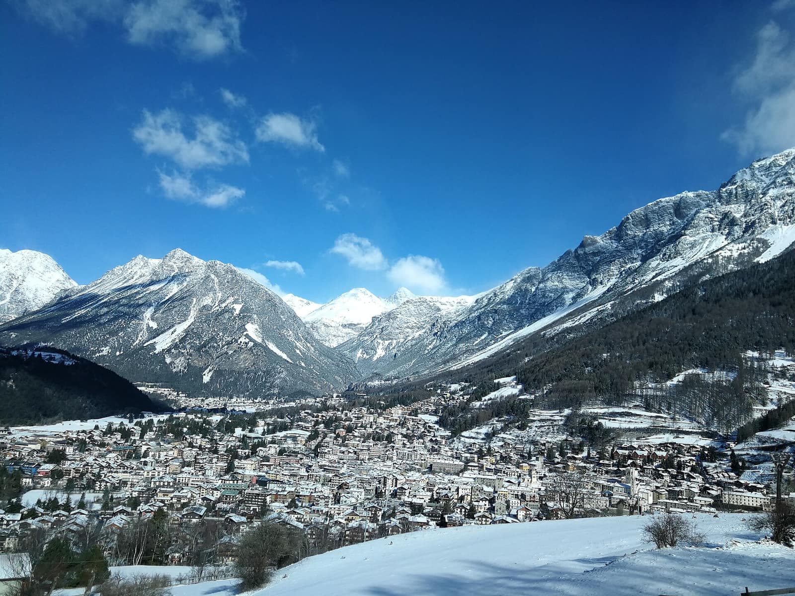 Bormio vista dall'alto d'inverno, con le case nella conca e le montagne innevate