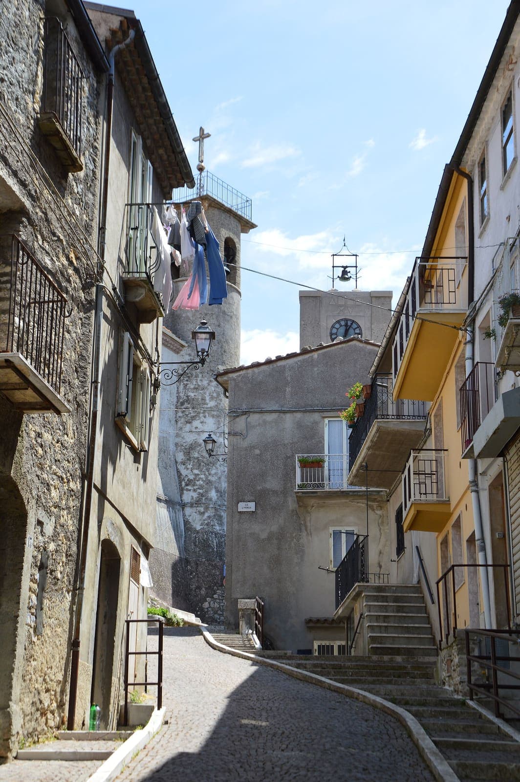 Vicolo in salita nel centro storico di Chiauci con il campanile e la torre dell'orologio