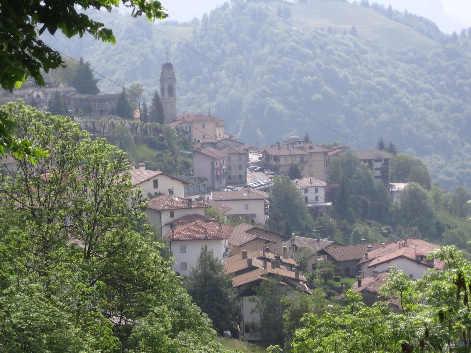 Dossena con le case e il campanile tra il verde della montagna