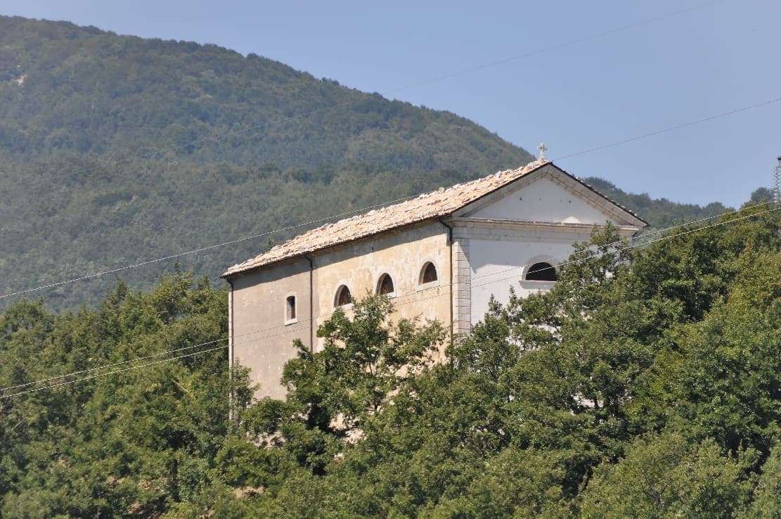 Una chiesa di Guardiaregia tra il verde, sotto il fianco boscoso del monte