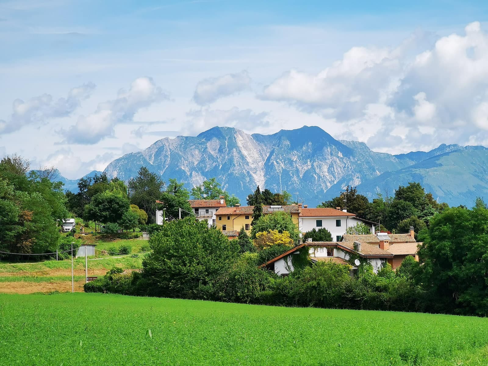 Case di San Tomaso di Majano tra il verde, con le montagne sullo sfondo