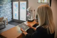 Persona al banco reception che usa un tablet, accoglienza clienti