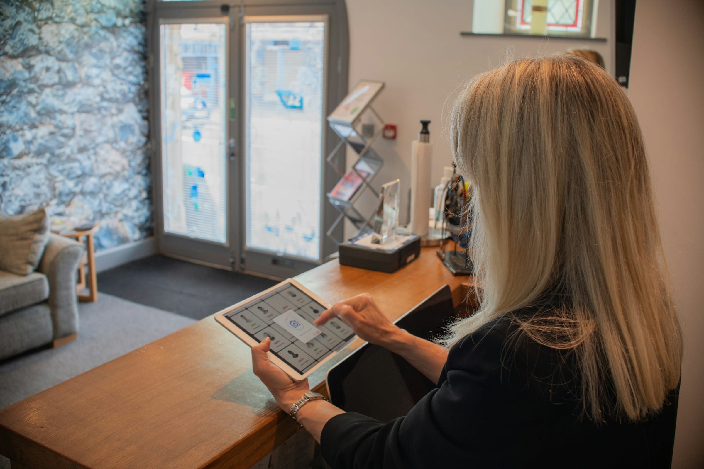 Persona al banco reception che usa un tablet, accoglienza clienti