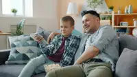 Padre e figlio guardano un film insieme sul divano di casa
