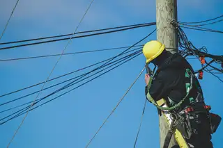 Tecnico con casco al lavoro su un palo della rete
